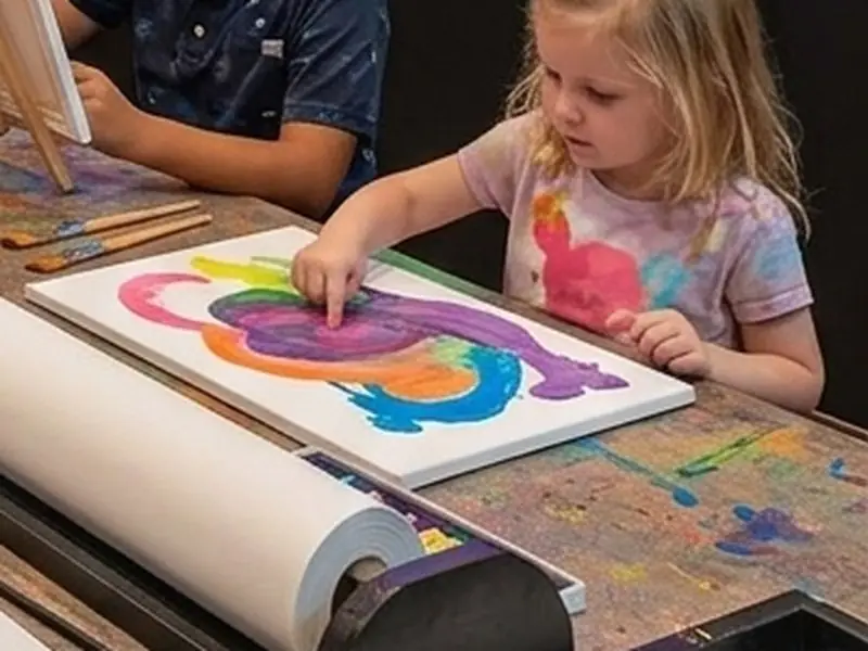 A young girl finger-painting a colourful canvas